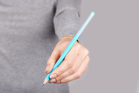Hand with blue pencil on grey.の写真素材