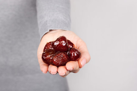 Hand with dried date on grey.