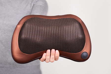 Hand with pillow for neck massage on grey.の写真素材