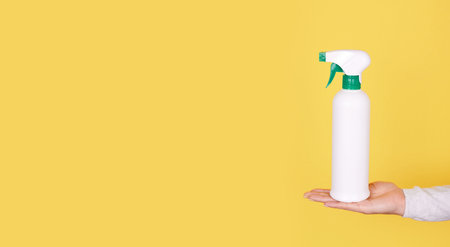 Hand with antiseptic in white spray bottle.