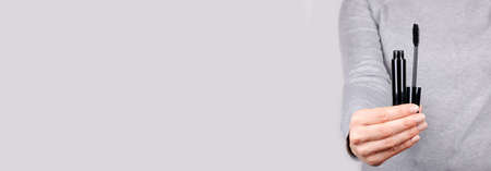 Hand with black eye mascara on grey.の写真素材