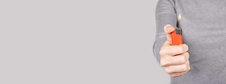 Hand with red flame lighter on grey.の写真素材