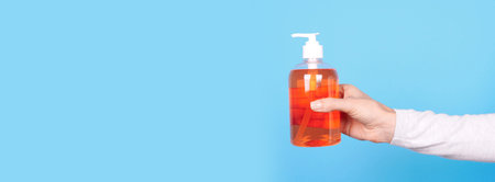Hand with orange soap bottle.