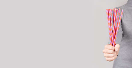 Hand with coctail straw on grey.の写真素材