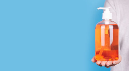 Hand with orange soap bottle.の写真素材