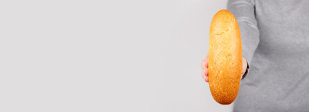 Hand with fresh bun on grey.