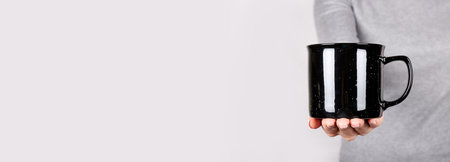 Hand with black cup on grey.の写真素材