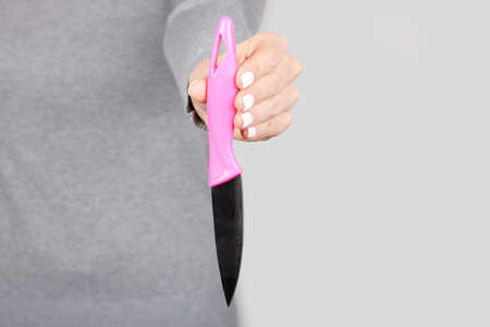 Hand with small kitchen knife on greyの写真素材