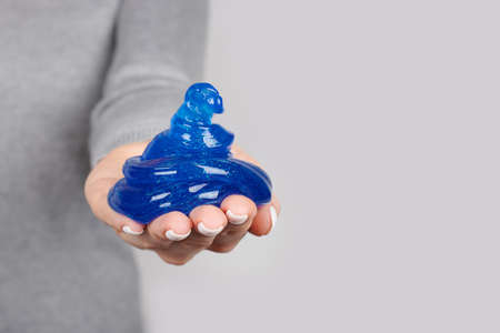 Hand with blue slime toy on greyの写真素材