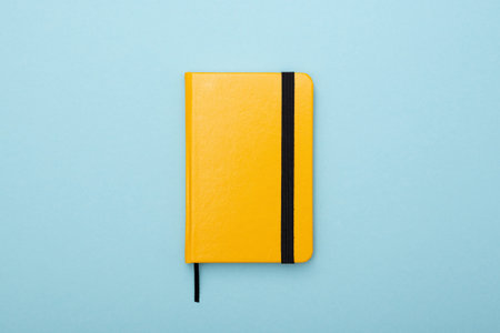 yellow notepad with a black bookmark lies on a blue background. Tool for work and studyの写真素材