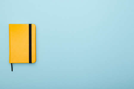 yellow notepad with a black bookmark lies on a blue background. Tool for work and studyの写真素材