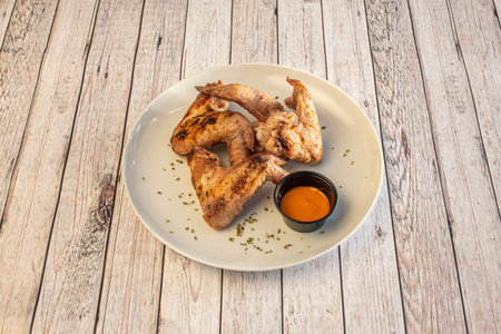 serving of fried chicken wings with buffalo-style sauce served on a white plateの写真素材