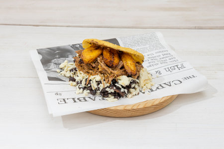 arepa pabellon with lots of fresh cheese, shredded pork and pieces of ripe banana on a Sunday newspaper sheetの写真素材