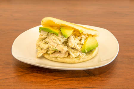 typical Venezuelan arepa recipe queen pepiada with lots of avocado and mayonnaise on wooden tableの写真素材