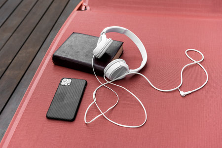 White headphones on terracotta-colored deck hammock with book and smartphone to spend some time of musical tranquilityの写真素材
