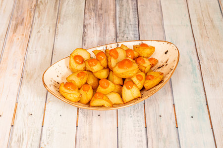 Popular Spanish tapa of hot sauce patatas bravas served in a white bowl with golden rimの写真素材