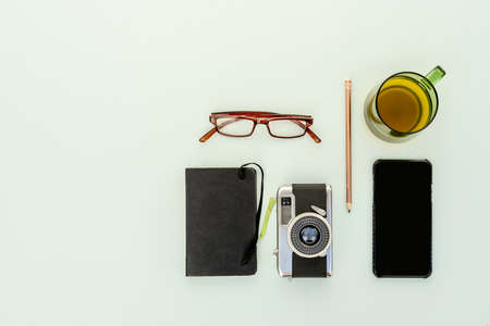 Top view of vintage photo camera with notepad, prescription glasses, teacup and smartphoneの写真素材