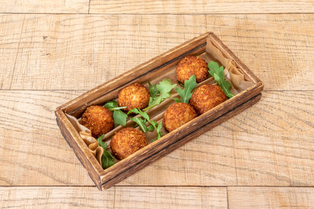 Tapa of Iberian croquettes with a little arugula in a curious wooden tray on a light wooden tableの写真素材
