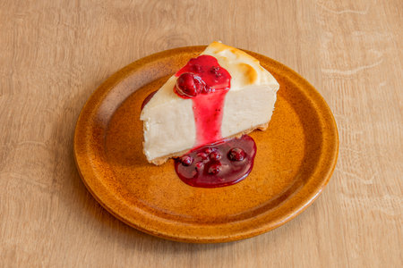 Delicious portion of homemade cheesecake with jam and syrupy ginda on brown plateの写真素材