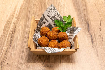 tapa of round Spanish croquettes with parsley served inside a wooden container on wooden backgroundの写真素材