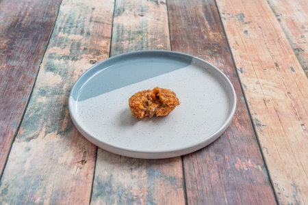 Salty croquette cut in half stuffed with meat in bolognese sauce on a nice plate with two shades of blue on the wooden tableの写真素材