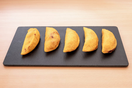 Colombian corn flour dumplings stuffed with meat fried in Spanish olive oil served on a black slate...
