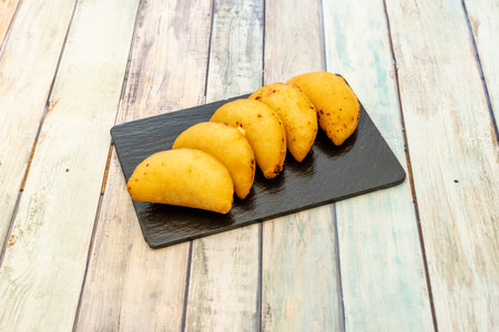 Ration of Colombian corn empanadas on black slate plate