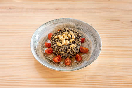 Black and white quinoa salad with nuts and cherry tomatoes in a beautiful gray-toned bowlの写真素材