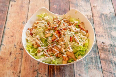 white bowl with typical Caesar salad with lettuce, chicken pieces and croutonsの写真素材
