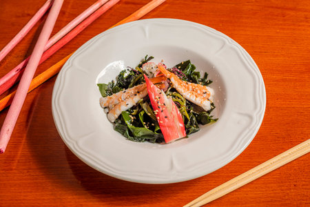 Wakame seaweed salad with surimi and scampi on white plateの写真素材