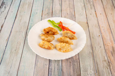 Fried Chinese dumplings gyozas stuffed with vegetables on round white plateの写真素材