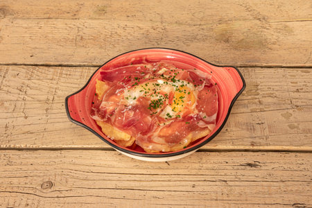 Spanish tapa of broken eggs with ham, fried potatoes with salt and corianderの写真素材