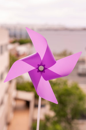 Purple pinwheel in the midday sun with trees and buildings in the background