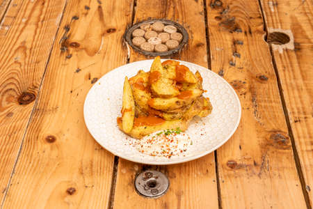 Spanish tapa of patatas bravas with separate sauces on nice white plate and pine wood tableの写真素材