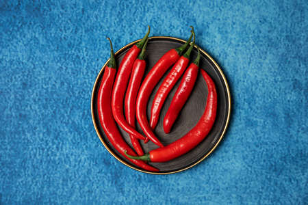 Handful of red hot cayenne peppers on vintage metal plate and blue cloth backgroundの写真素材