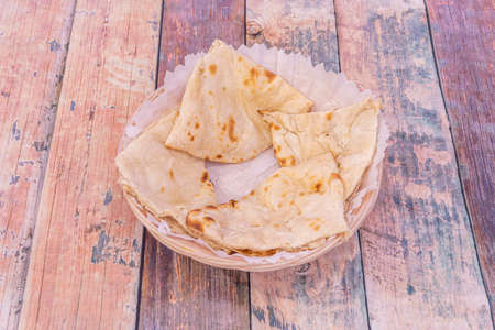 Chopped cheese naan placed in light wicker basket on wooden backgroundの写真素材