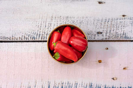 Top view photography of handful of small red bell peppers on pastel painted wood and metal nailsの写真素材