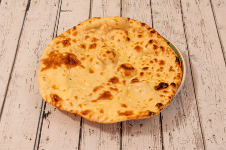 Hindu garlic bread wafer, naan, cooked with oil and cheese on white table