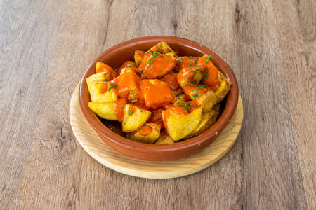 Spectacular portion of patatas bravas a la madrileÃ±a in a clay pot on a wooden tableの素材 [FY310171286600]