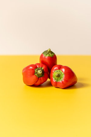 Front image of three red peppers on yellow table and white background.の写真素材