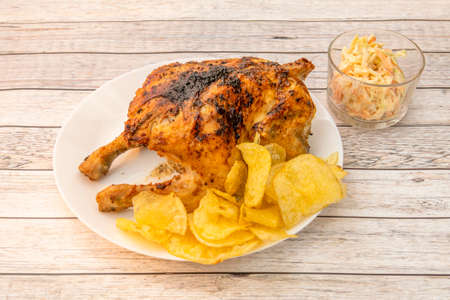 Grilled whole chicken with French fries chips and coleslaw on white tableの写真素材