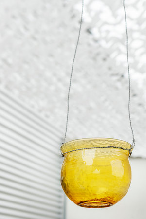 Empty yellow glass candle holder with industrial metal wall background and white awningの写真素材