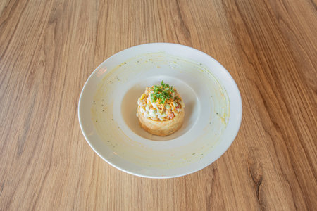 Typical Spanish tapa of Russian salad with parsley and mayonnaise on white plate