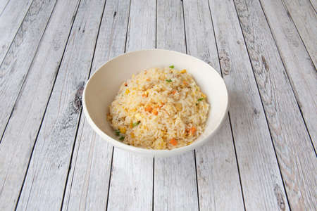 White bowl of rice three delights cooked in a Chinese restaurant with white tablesの写真素材