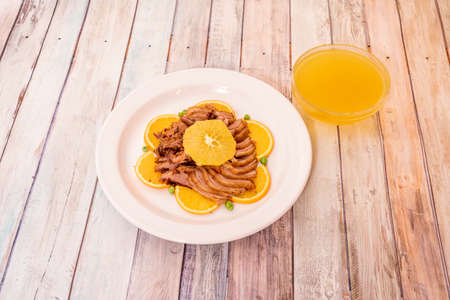 typical Chinese recipe of fried duck sliced with orange on a white porcelain plate and bowl with lots of orange sauceの写真素材
