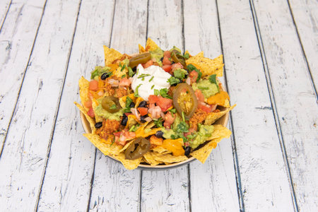 Mexican Corn Nachos with Shredded Chicken, Rabid JalapeÃ±os, Cream Cheese, Cheddar Cheese, Black Beans, Diced Tomato, and Chopped Parsleyの写真素材