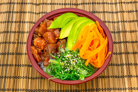 Home delivery bowl with marinated chopped salmon, wakame seaweed with sesame and poppy seeds, carrot...