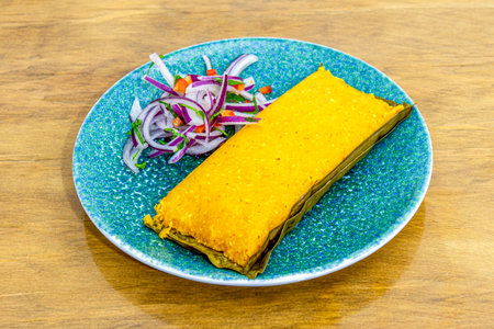 Tamale cooked in a Peruvian restaurant with purple onion and parsley as garnishの写真素材