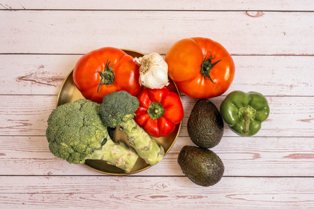 Golden bowl with tomatoes and peppers, ripe avocados and green peppers and broccoli with garlic on...