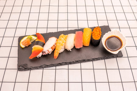 tray of assorted raw nigiri with soy sauce on Japanese white rice. Salmon and red tuna,...